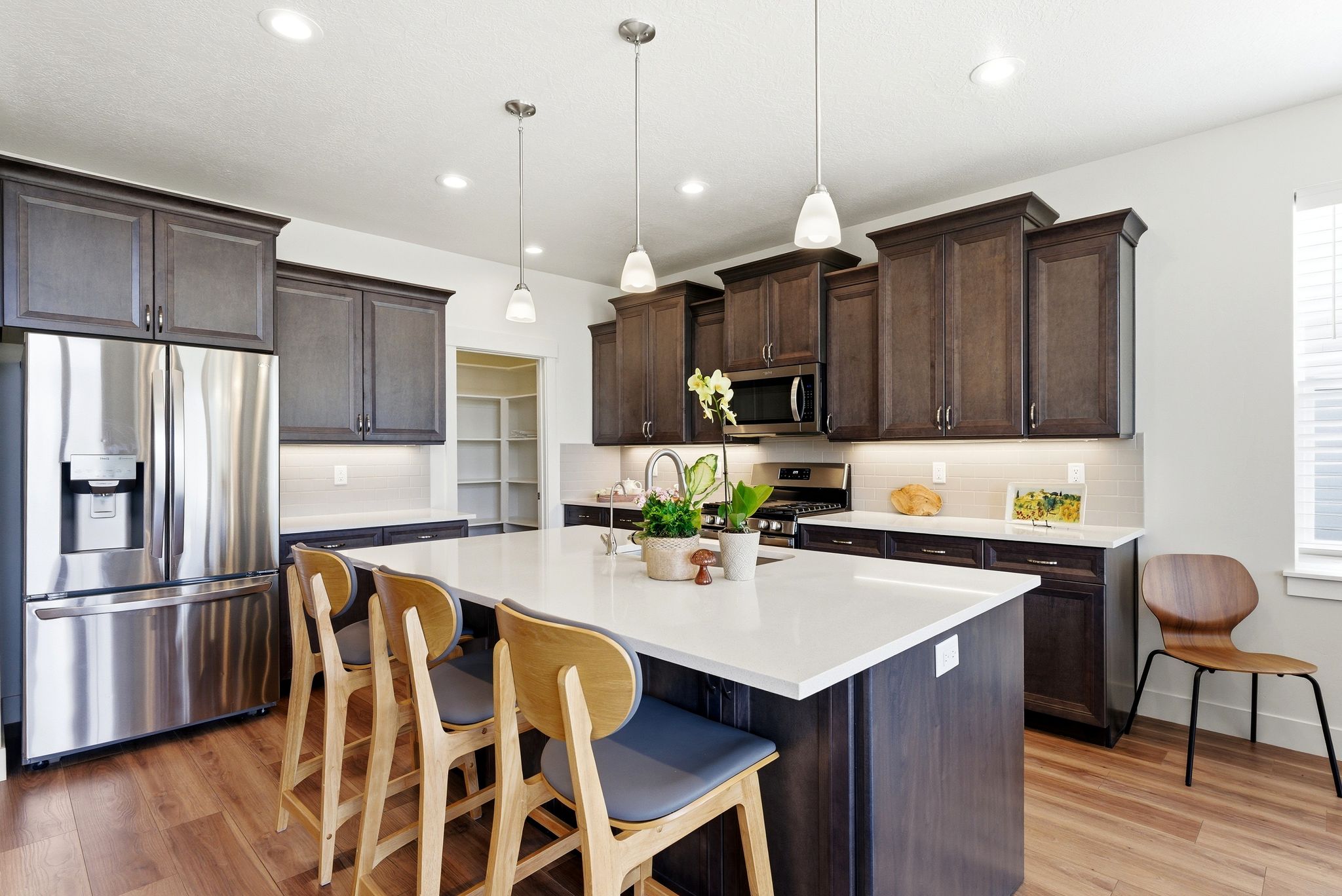 Kitchen featuring a central island with countertop seating, dark wood-finish cabinetry, stainless steel appliances, and wood-finish flooring