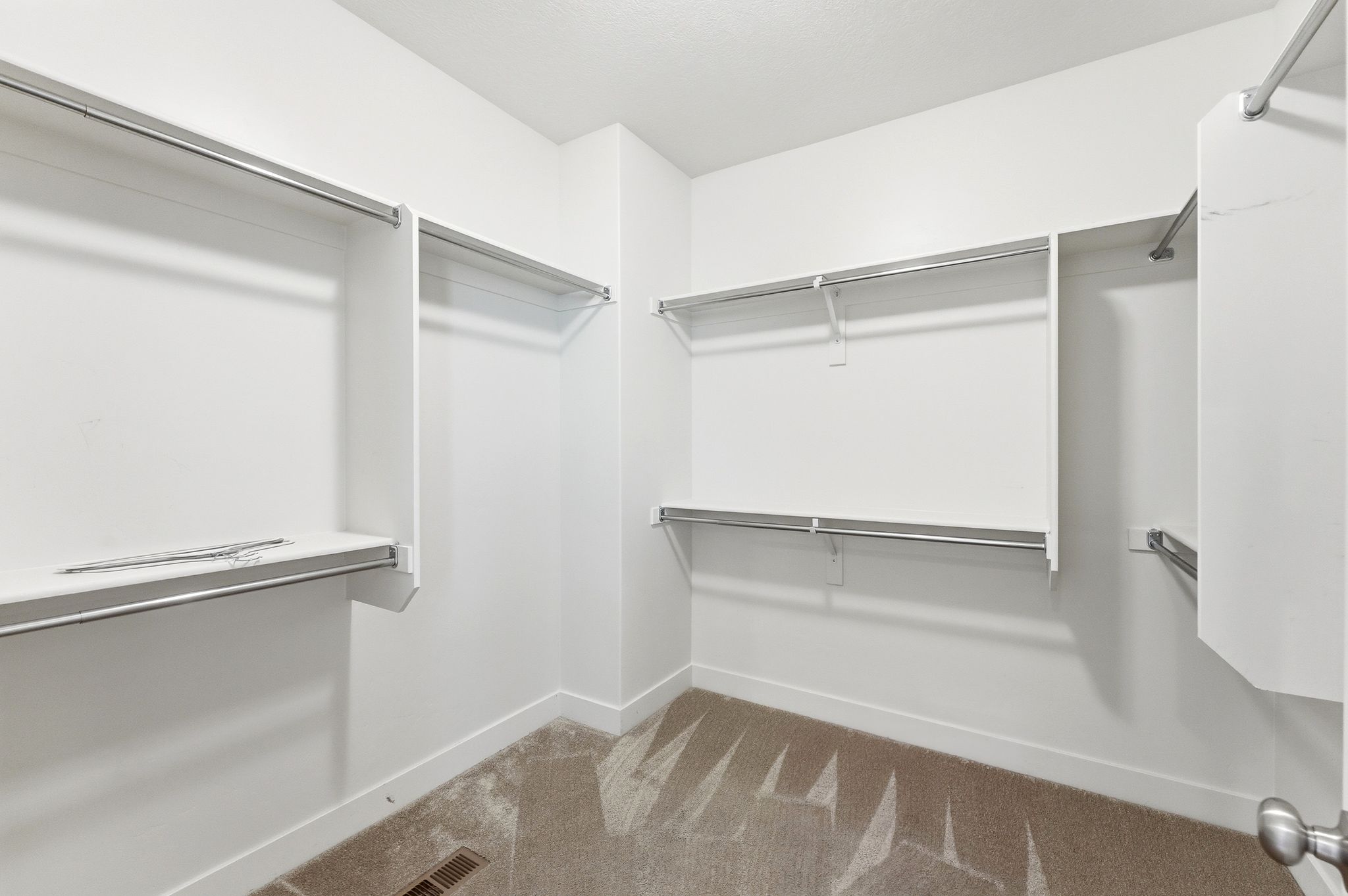 Walk-in closet featuring extensive built-in shelving and multiple hanging rods