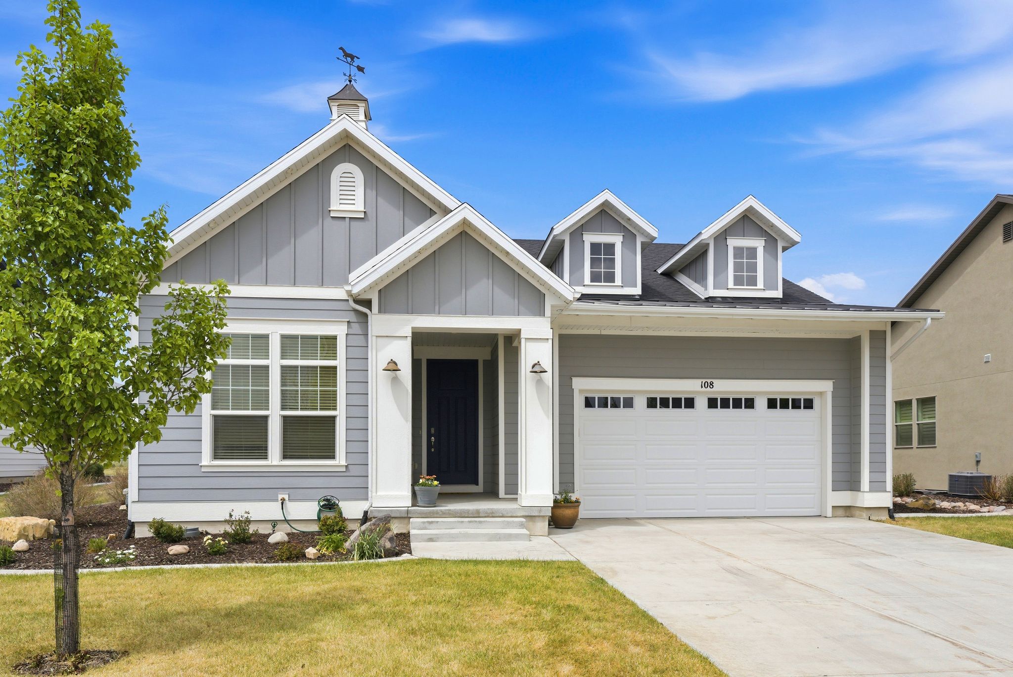 Contemporary single-story residence featuring light gray siding and white trim