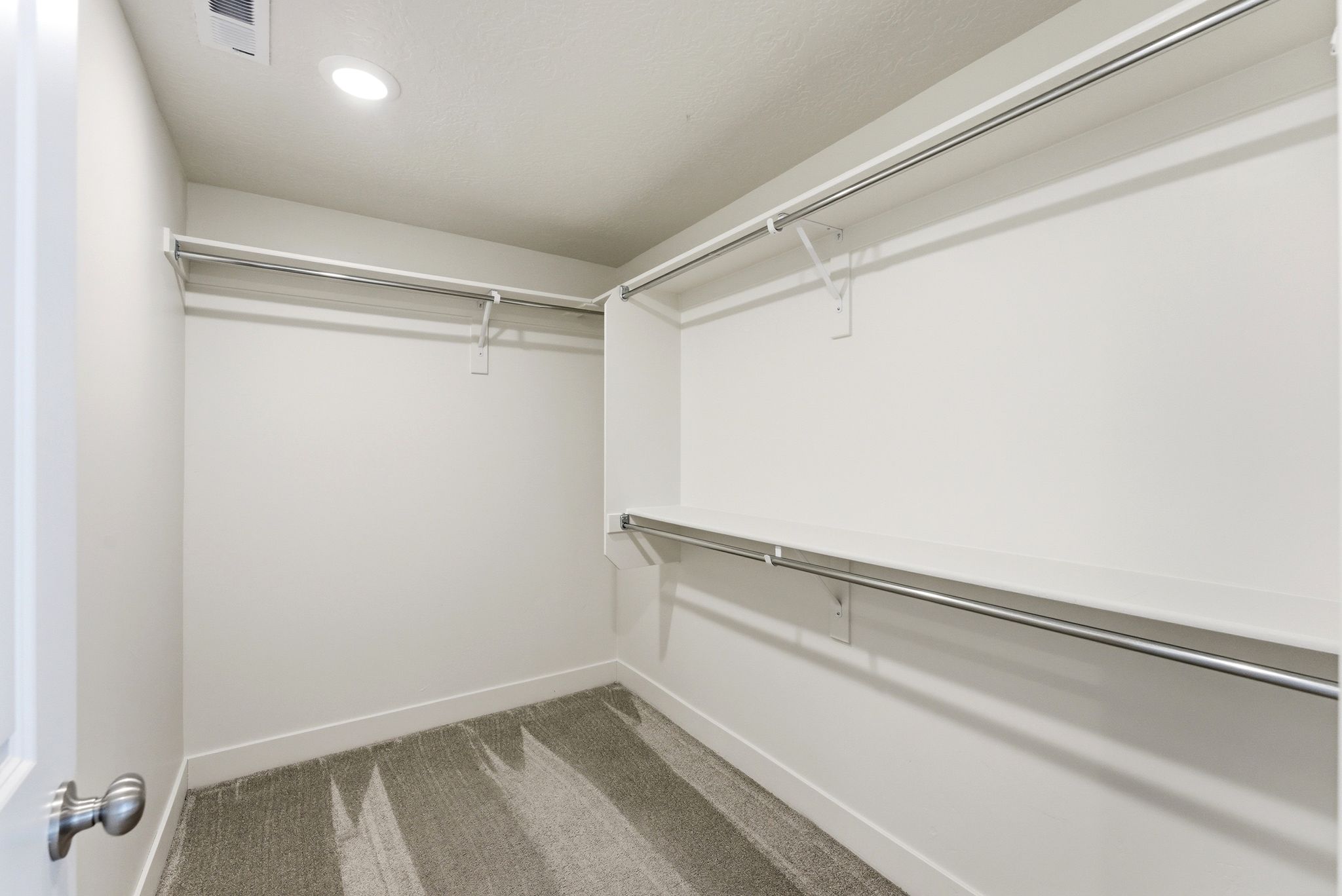 Walk-in closet featuring built-in shelving, chrome hanging rods, recessed ceiling lighting, and soft carpet flooring