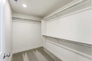 Walk-in closet featuring built-in shelving, chrome hanging rods, recessed ceiling lighting, and soft carpet flooring