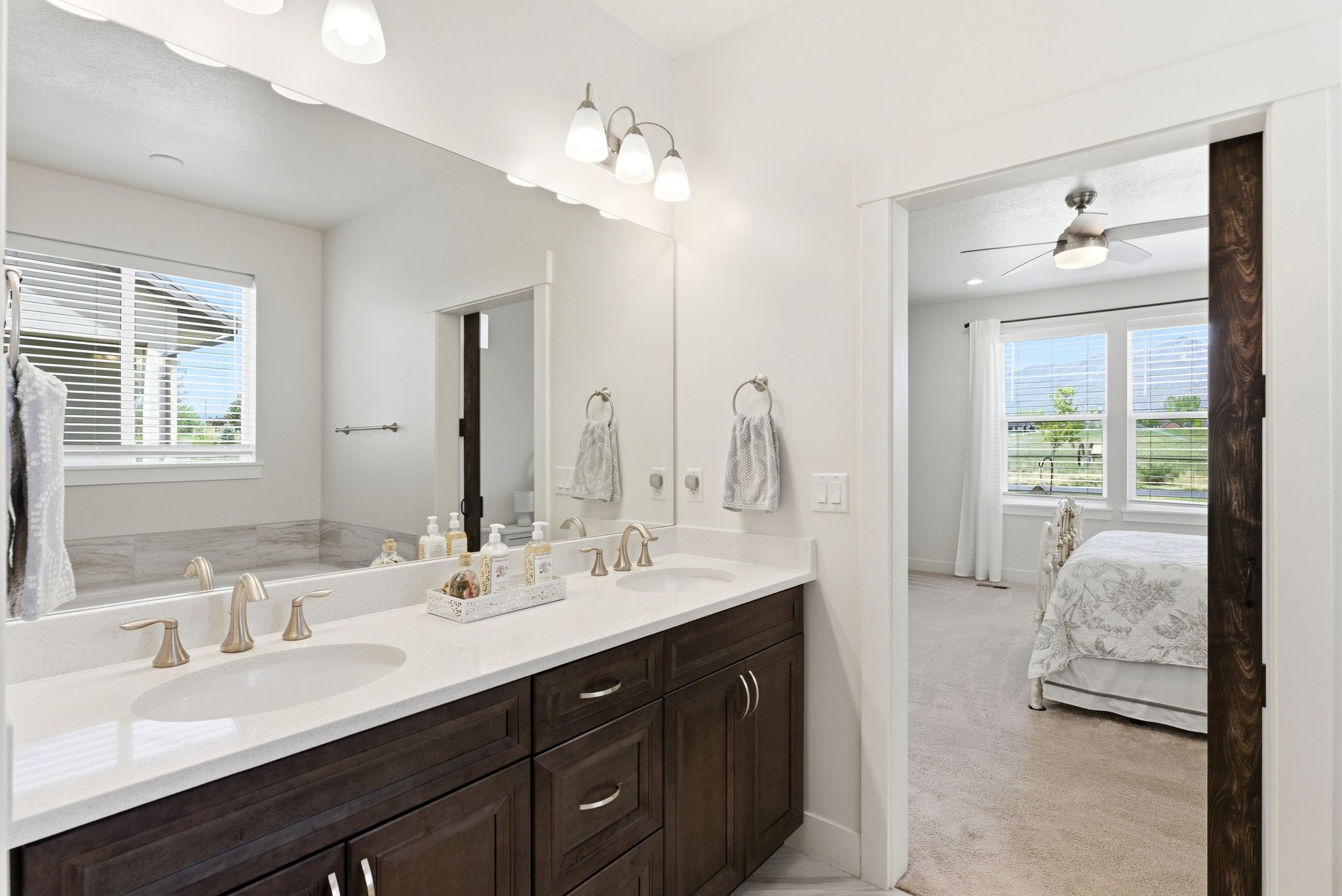 Double vanity featuring dual undermount sinks, brushed nickel faucets, and dark wood-finish cabinetry with silver-tone hardware