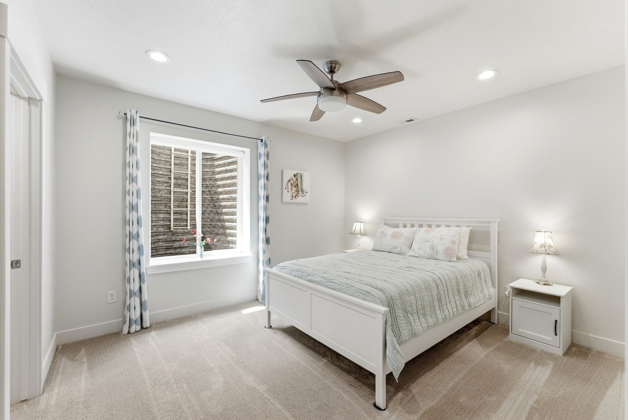 Bright bedroom featuring light neutral walls and coordinating carpet flooring