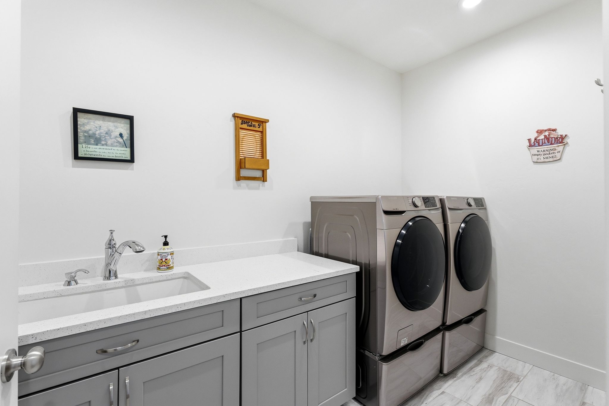 Laundry area featuring a utility sink, light gray cabinetry, white countertops, and wood-finish tile flooring