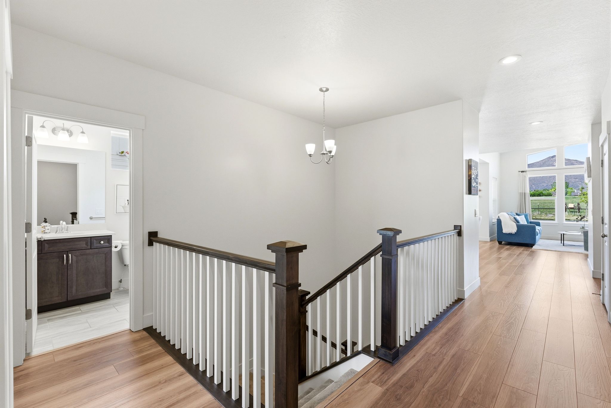 Hallway with wood-finish flooring, white walls, and a dark wood and white baluster staircase