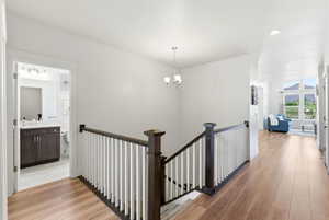 Hallway with wood-finish flooring, white walls, and a dark wood and white baluster staircase