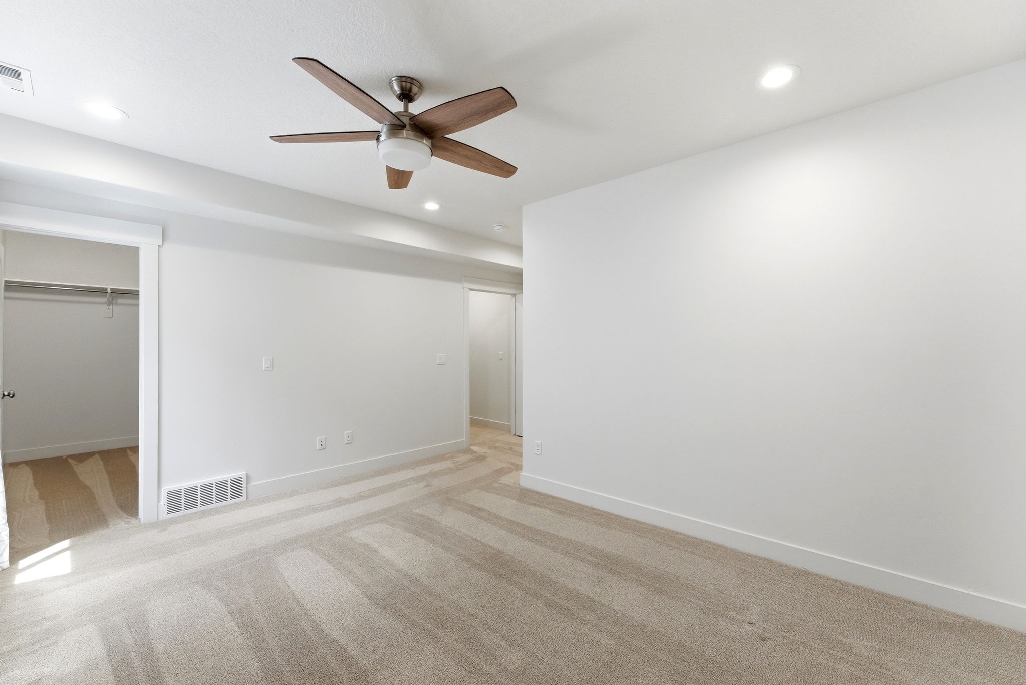 Spacious room featuring neutral carpeting, a ceiling fan with integrated lighting, and recessed ceiling lights
