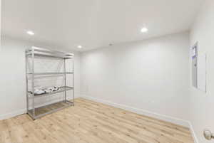 Spacious room featuring wood-finish flooring, white baseboards, recessed lighting, and a neutral color palette