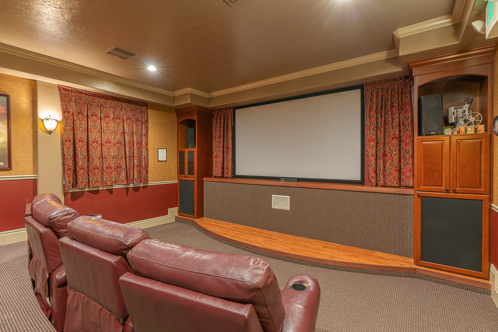 Dedicated media room featuring a large projection screen, built-in cabinetry, and integrated sound system