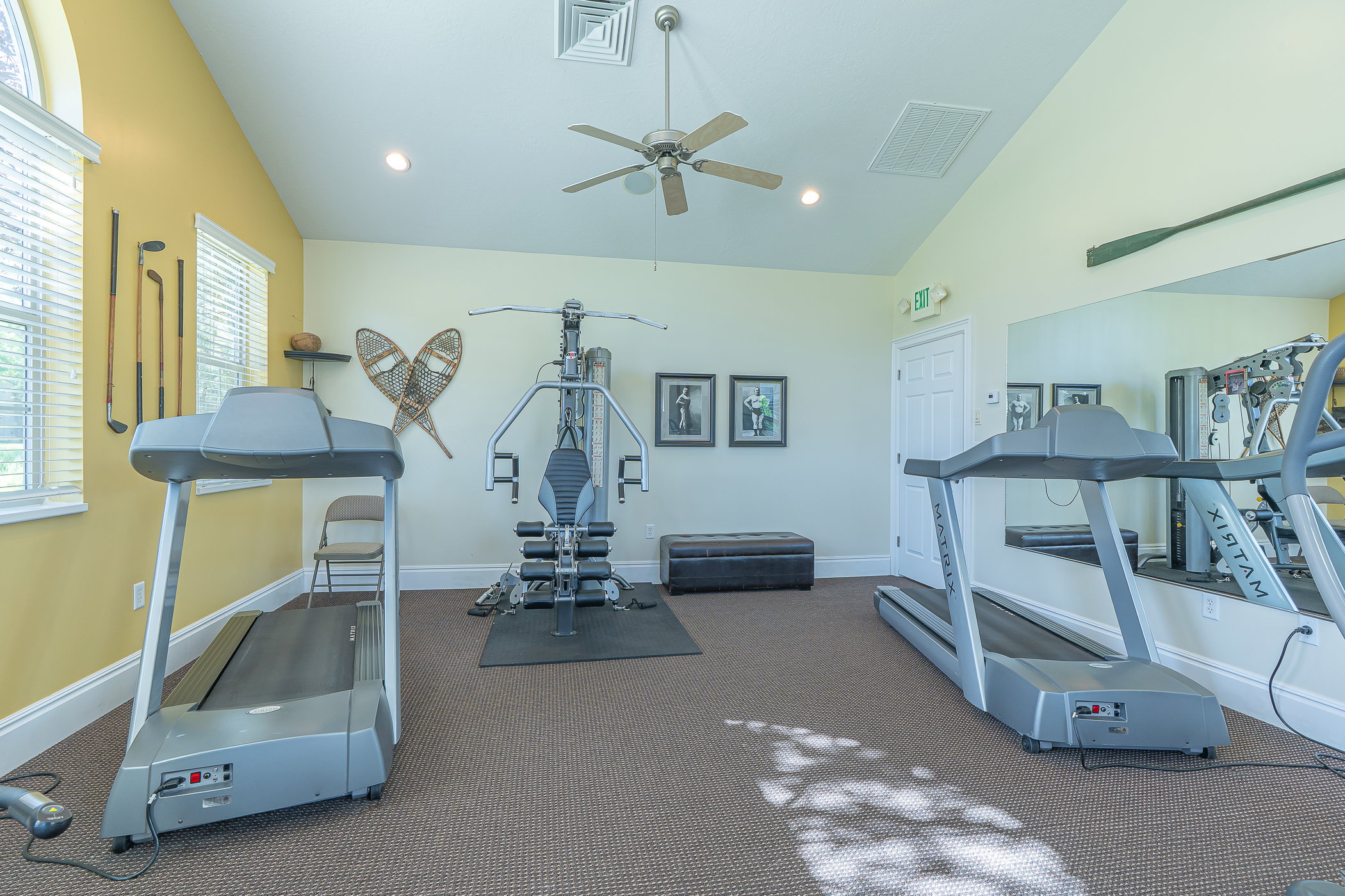 Carpeted exercise room with vaulted ceilings, a ceiling fan, and recessed lighting