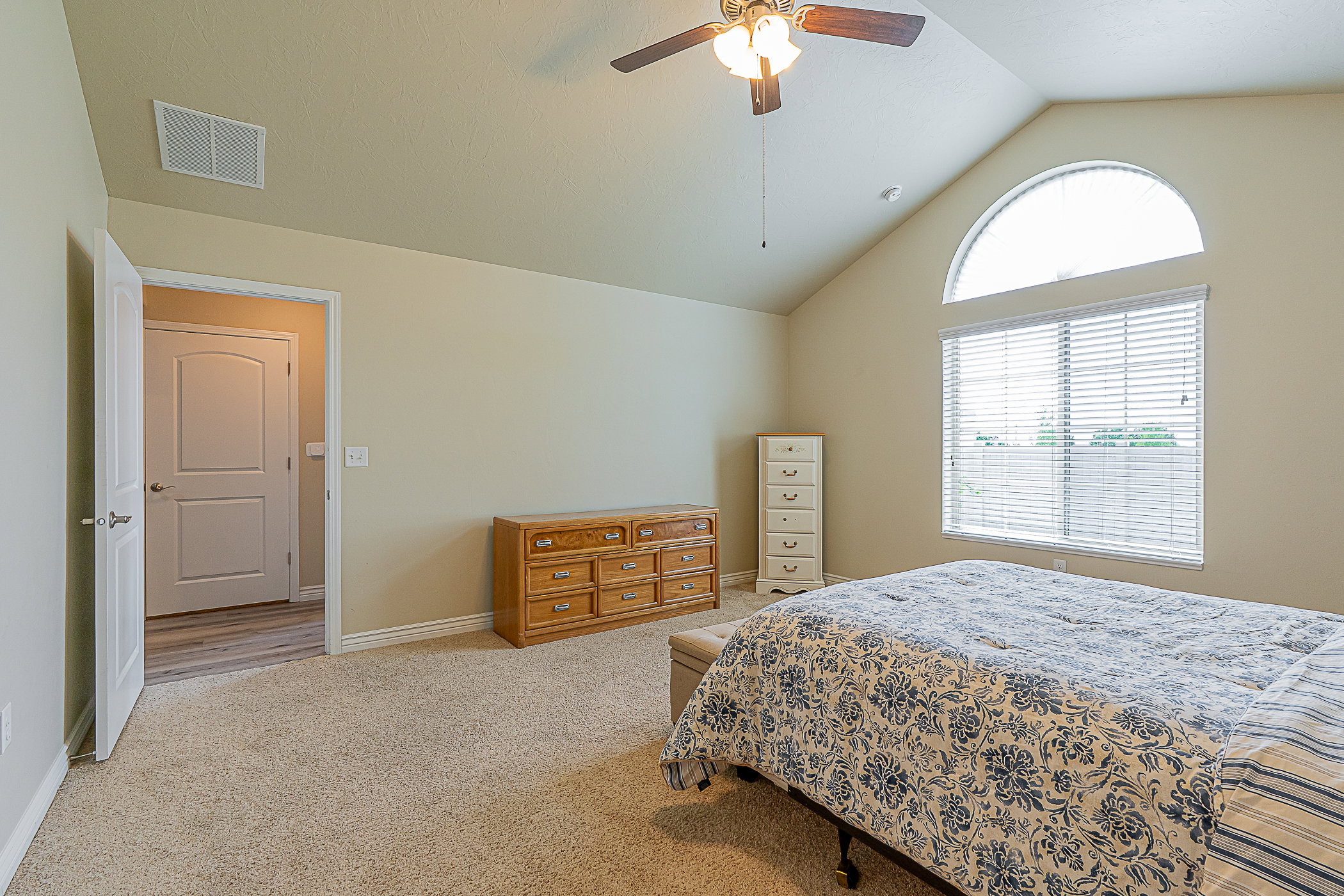 Carpeted room with a vaulted ceiling and an arched transom window