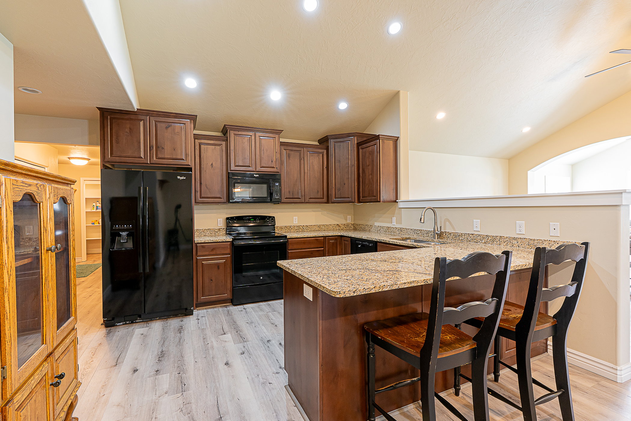 Kitchen featuring wood-finish flooring, granite countertops, and dark wood cabinetry