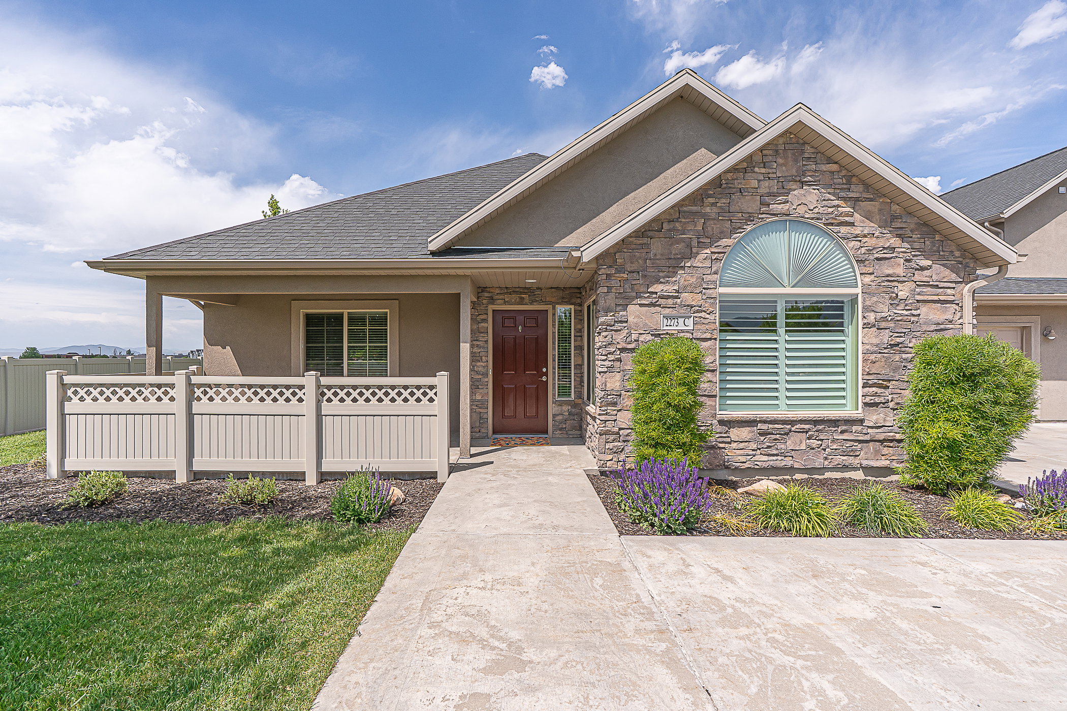 Stone veneer exterior with an arched window, covered entryway, and a solid wood front door