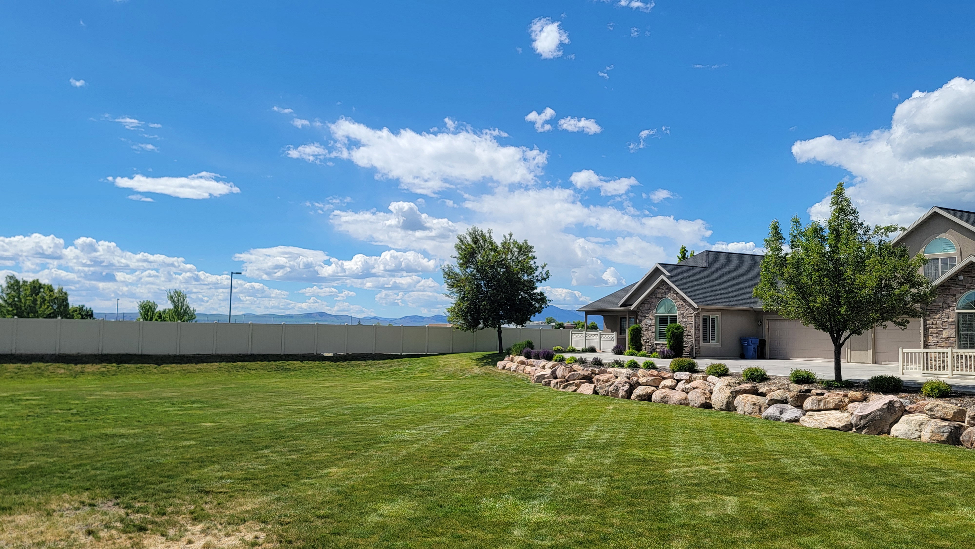 Expansive green lawn bordering a rock-lined flower garden bed