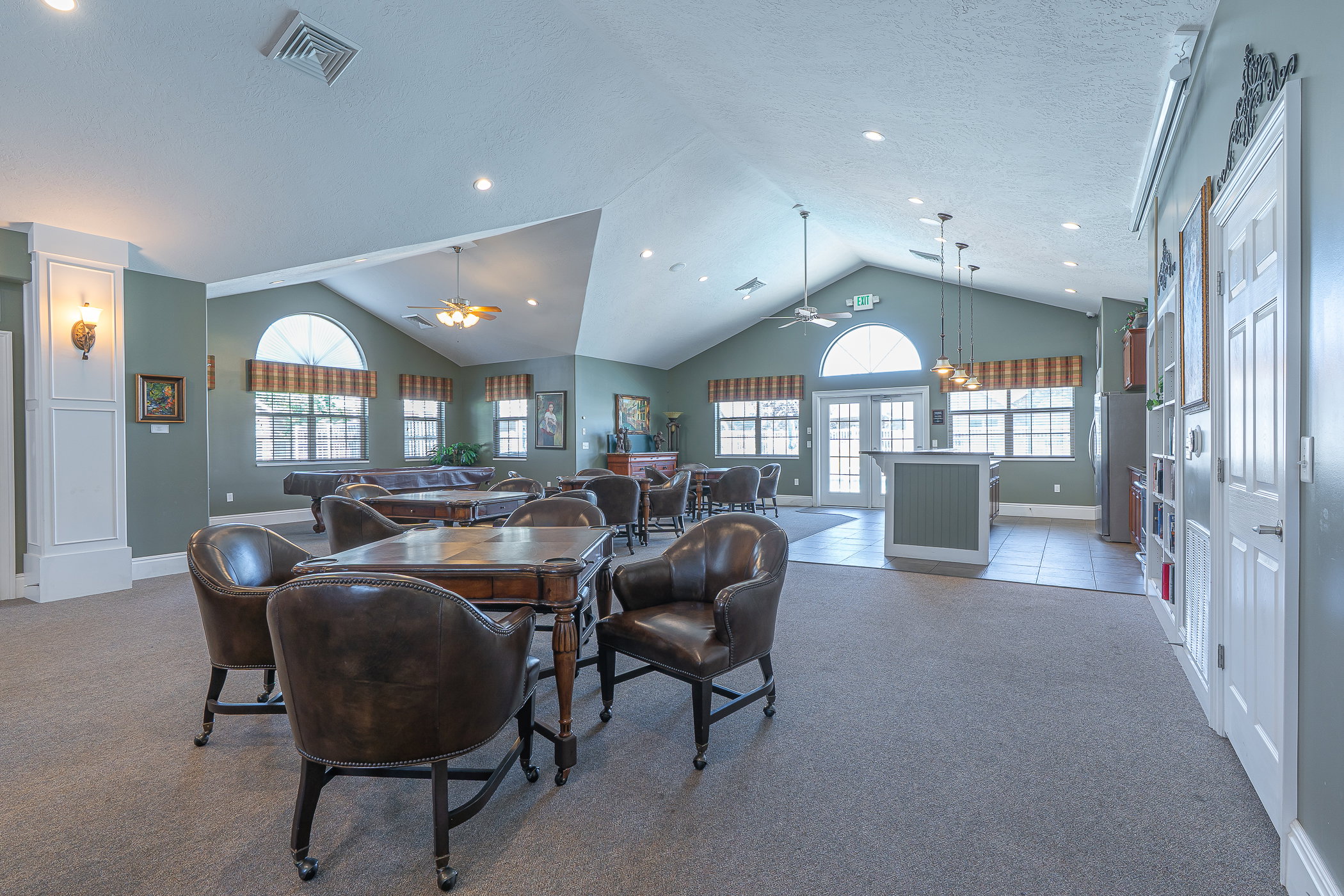 Spacious common room featuring vaulted ceilings, recessed lighting, and a blend of carpet and tile flooring
