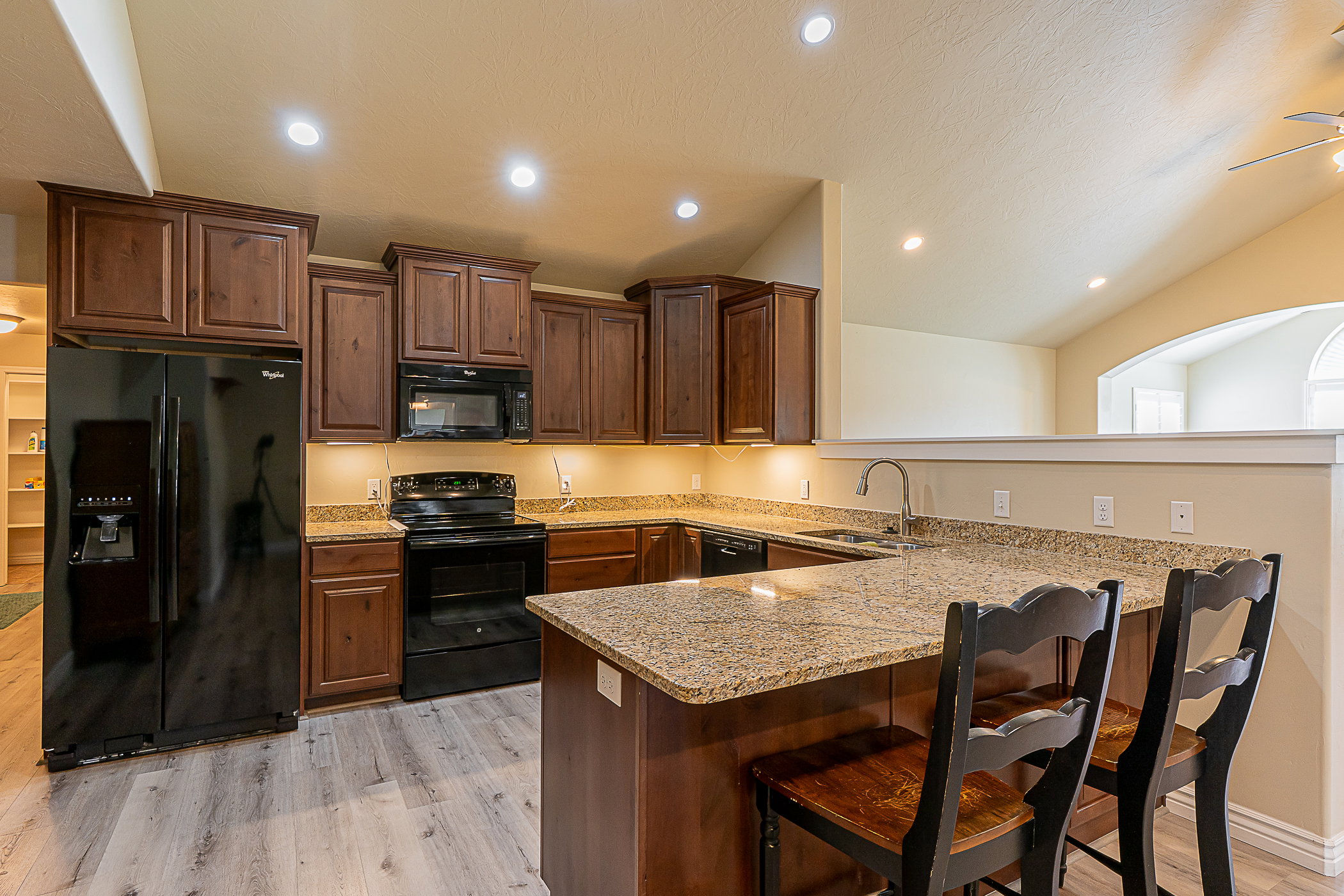 Kitchen featuring wood-finish cabinetry, granite-style countertops, and light wood-finish flooring; features UNDERCABINET lighting