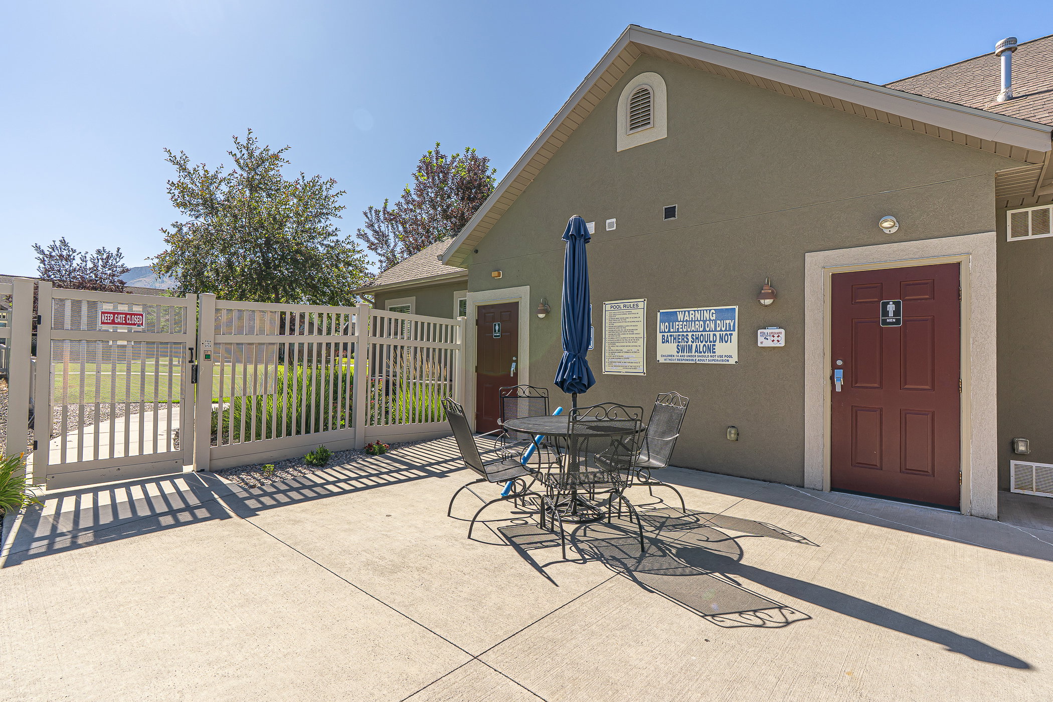 Outdoor patio area featuring a concrete surface, a stucco building exterior, and a light-colored privacy fence