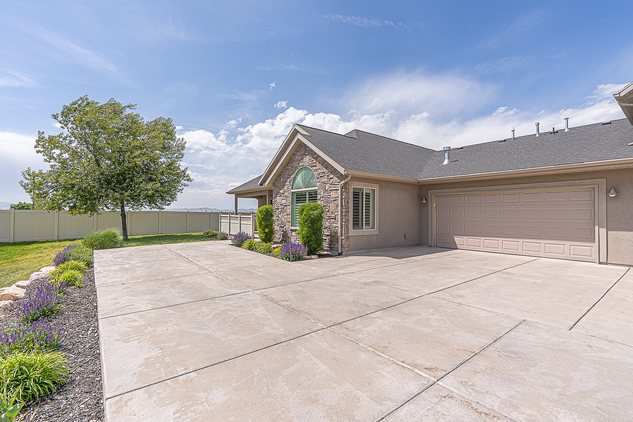 Exterior featuring stone facade detailing, arched window, and a spacious concrete driveway