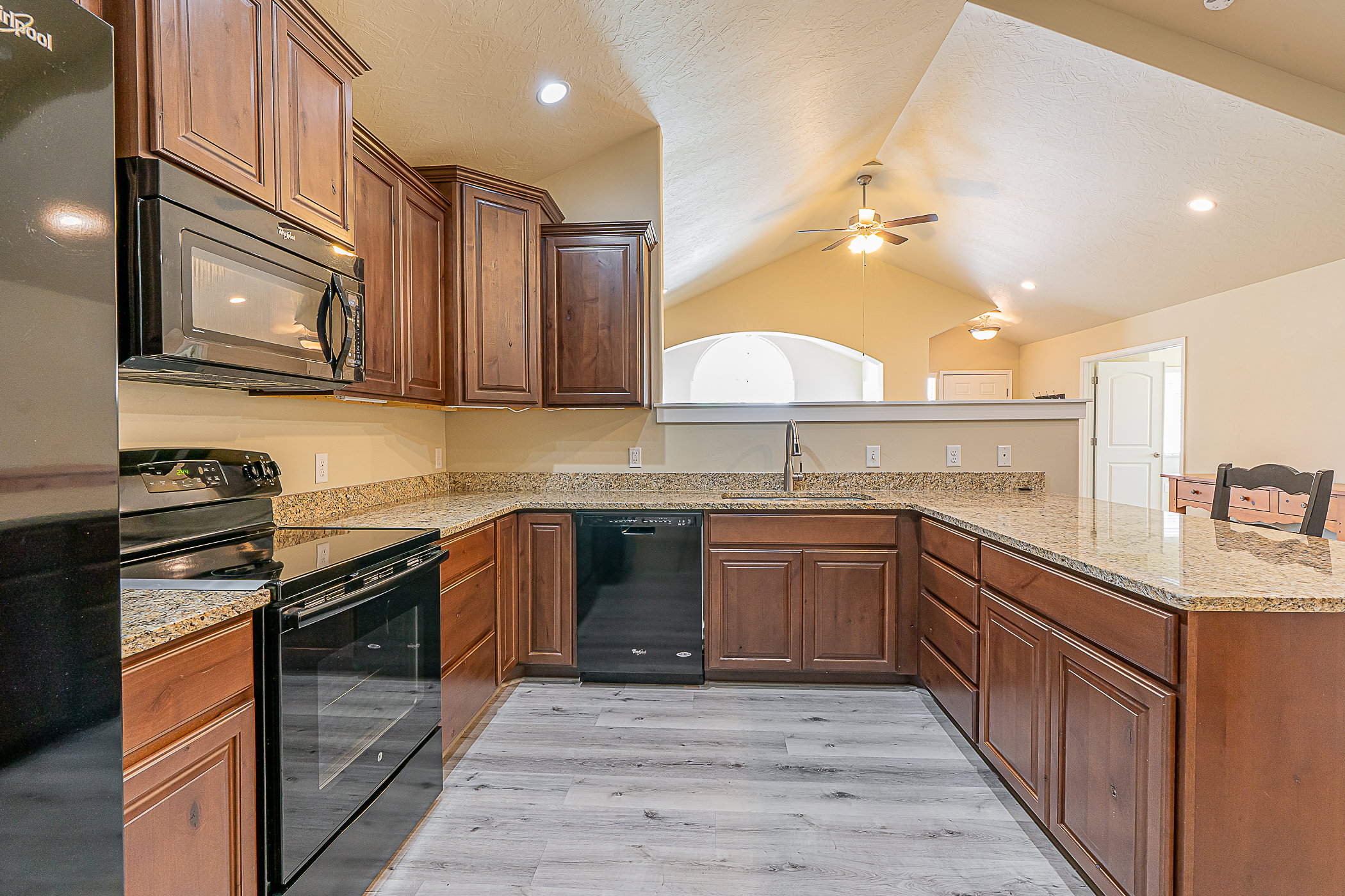 Kitchen featuring wood-finish cabinetry, speckled countertops, and a black appliance suite including a range, microwave, and dishwasher