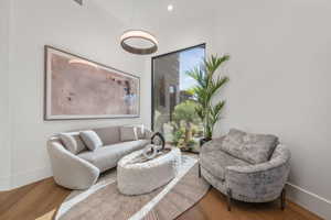 Bright interior space featuring a floor-to-ceiling window, wood-finish flooring, and a contemporary circular pendant light fixture