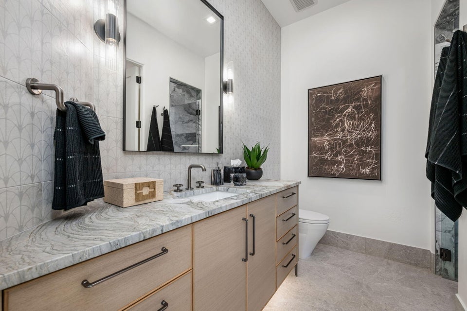 Contemporary vanity featuring light wood-finish cabinetry, a single integrated sink, and dark hardware
