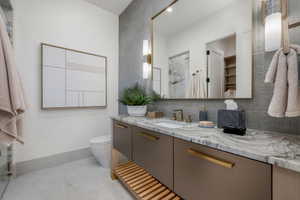 Bathroom vanity featuring a natural stone countertop with integrated sink, bronze-finish fixtures, and a large framed mirror