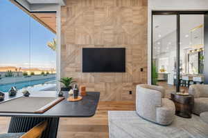 Floor-to-ceiling glass wall, wood-finish flooring, patterned wood wall paneling, sliding glass door, and a built-in entertainment area