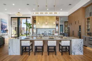 Gourmet kitchen featuring a waterfall island, custom wood cabinetry, stainless steel appliances, and wood-finish flooring