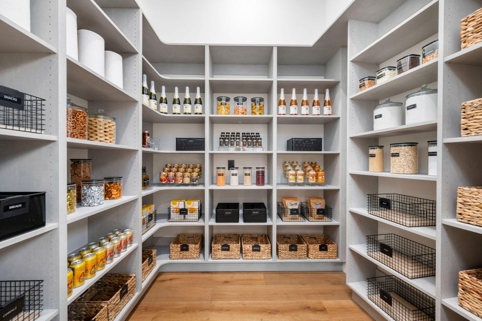 Custom-built pantry featuring extensive shelving, corner storage, adjustable shelf heights, integrated lighting, and wood-finish flooring
