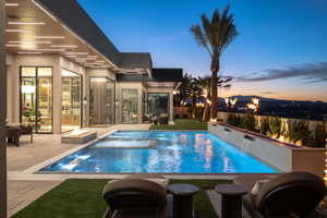 Contemporary outdoor pool with integrated spa, adjacent fire pit, and multiple water features