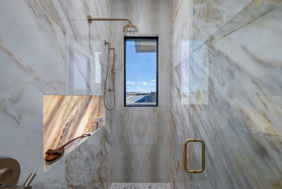 Walk-in shower with full-height stone-look tile walls, an integrated niche with backlighting, a fixed showerhead, and a handheld shower attachment