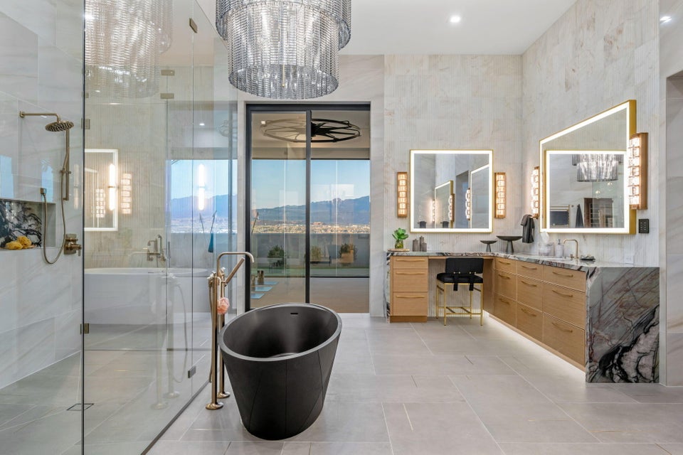 Contemporary bathroom featuring a freestanding black soaking tub, a spacious glass-enclosed shower with a rainfall showerhead, and dual vanities with illuminated mirrors