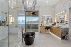 Contemporary bathroom featuring a freestanding black soaking tub, a spacious glass-enclosed shower with a rainfall showerhead, and dual vanities with illuminated mirrors