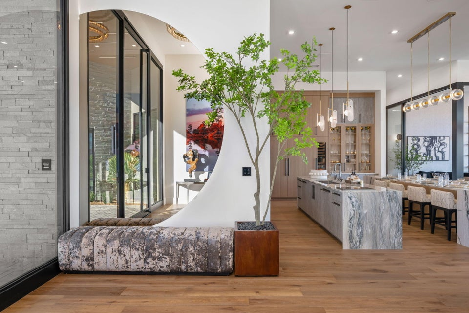 Open-concept living area featuring wide-plank wood-finish flooring, a large kitchen island with a stone finish, and built-in cabinetry with integrated appliances