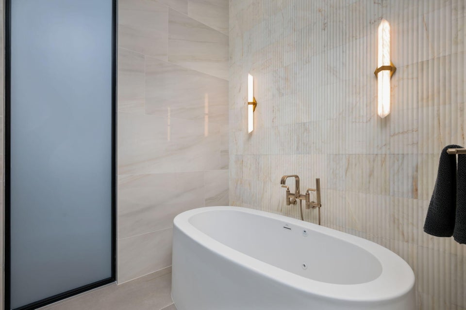 Freestanding oval soaking tub with wall-mounted bronze-finish faucet