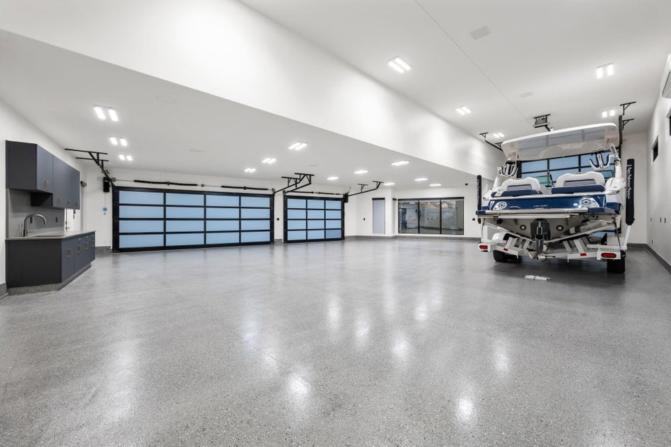 Spacious garage featuring two translucent panel garage doors, concrete flooring, recessed lighting, and built-in cabinetry with a sink