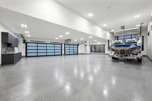 Spacious garage featuring two translucent panel garage doors, concrete flooring, recessed lighting, and built-in cabinetry with a sink