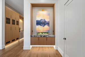 Built-in alcove with a polished stone countertop and wood-finish cabinetry, illuminated by integrated lighting and a wall-mounted fixture