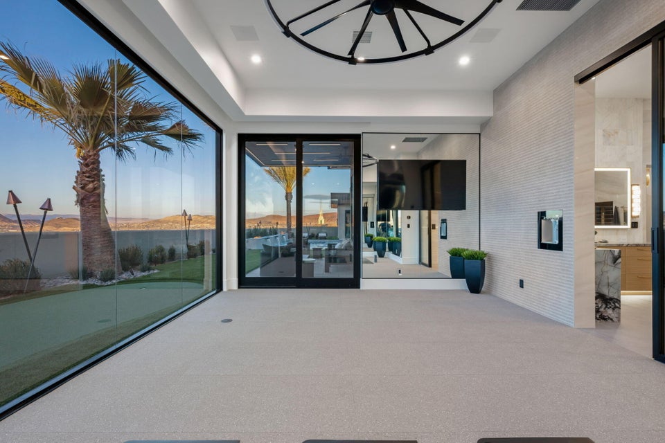 Expansive floor-to-ceiling glass wall, light gray carpet flooring, recessed lighting, and a modern ceiling fixture