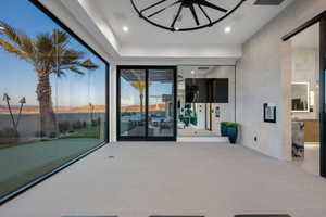 Expansive floor-to-ceiling glass wall, light gray carpet flooring, recessed lighting, and a modern ceiling fixture