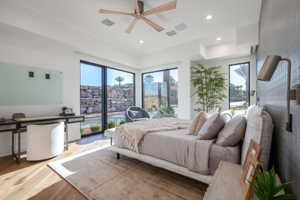 Bedroom featuring wide plank wood-finish flooring, a contemporary ceiling fan, recessed lighting, and expansive windows