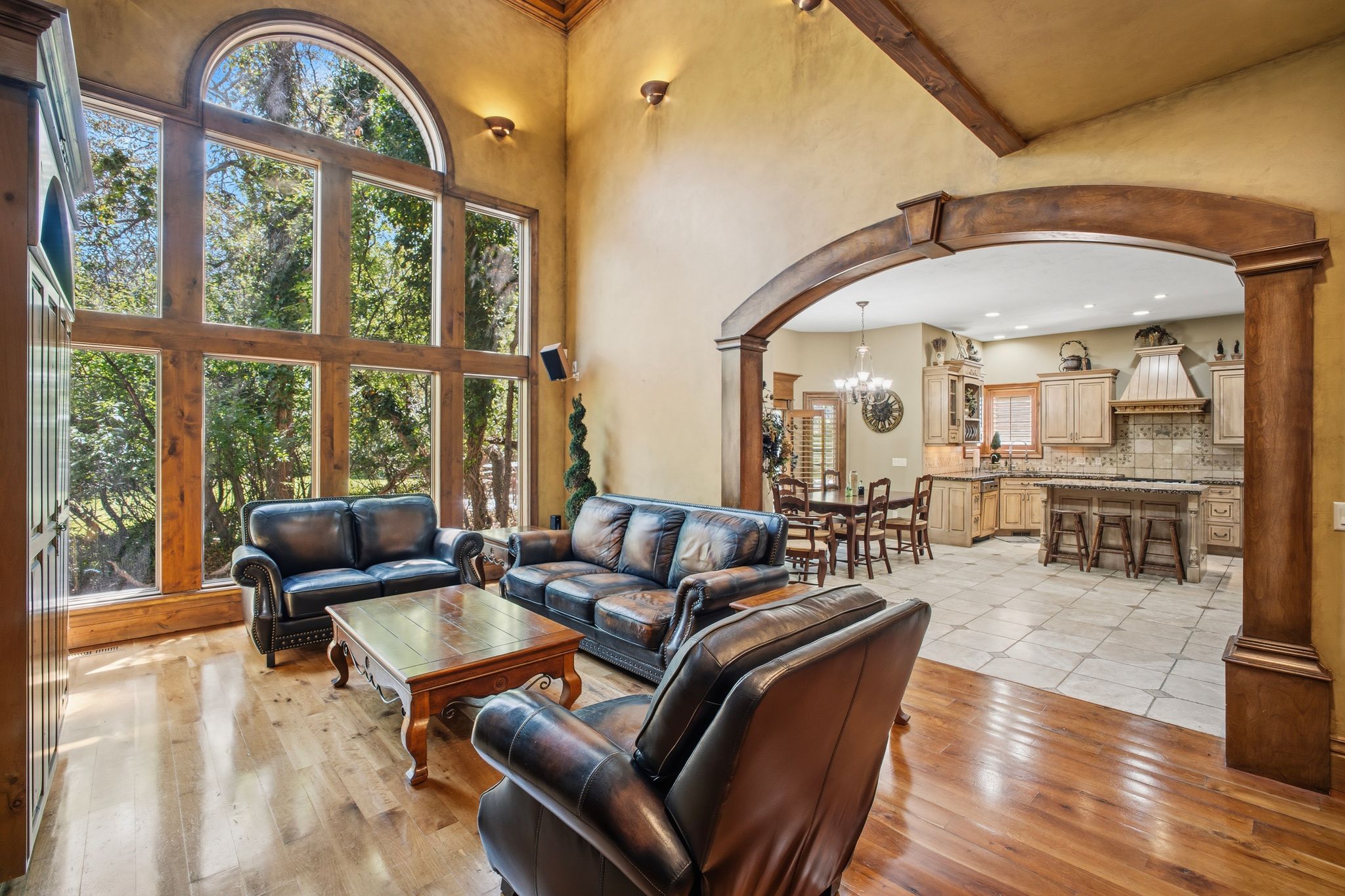 Great room featuring a vaulted ceiling, wood-finish flooring, and a large arched window wall