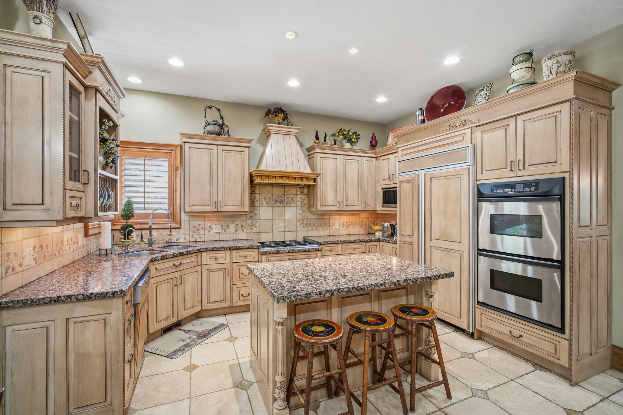 Kitchen featuring light-toned cabinetry with crown molding and fluted details, granite countertops, and an integrated double oven