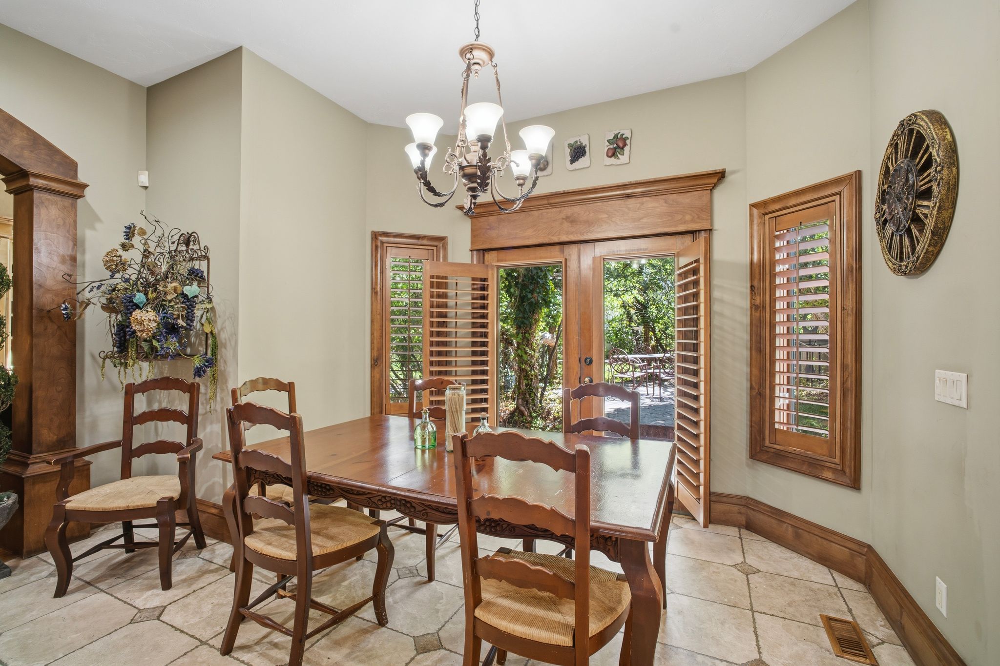Dining area featuring wood-finish French doors and shuttered windows, a decorative chandelier, and tile flooring