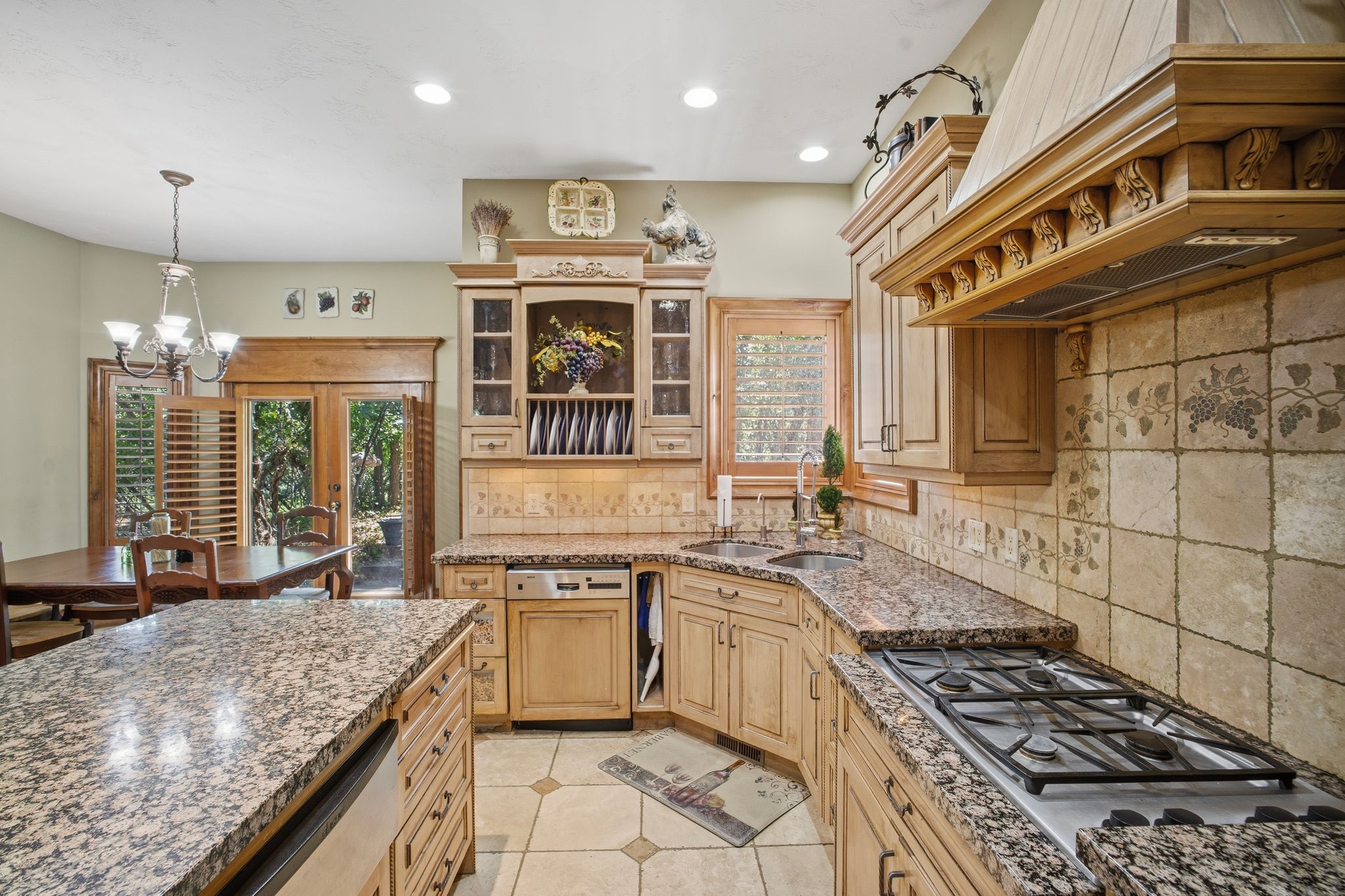 Kitchen featuring light wood cabinetry, granite countertops, tile backsplash, and a gas range