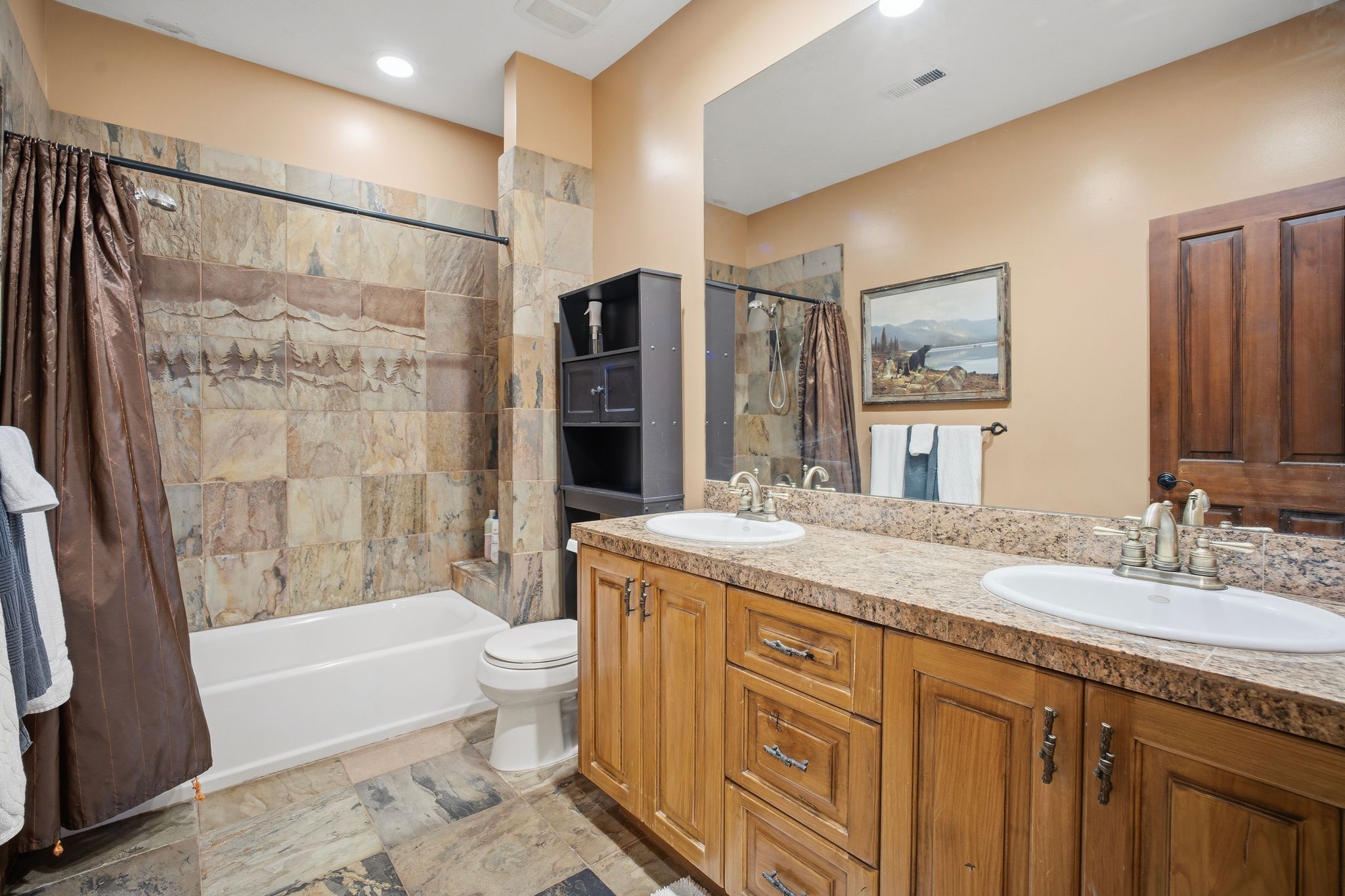 Bathroom featuring a dual vanity with light-toned countertops and wood-finish cabinetry