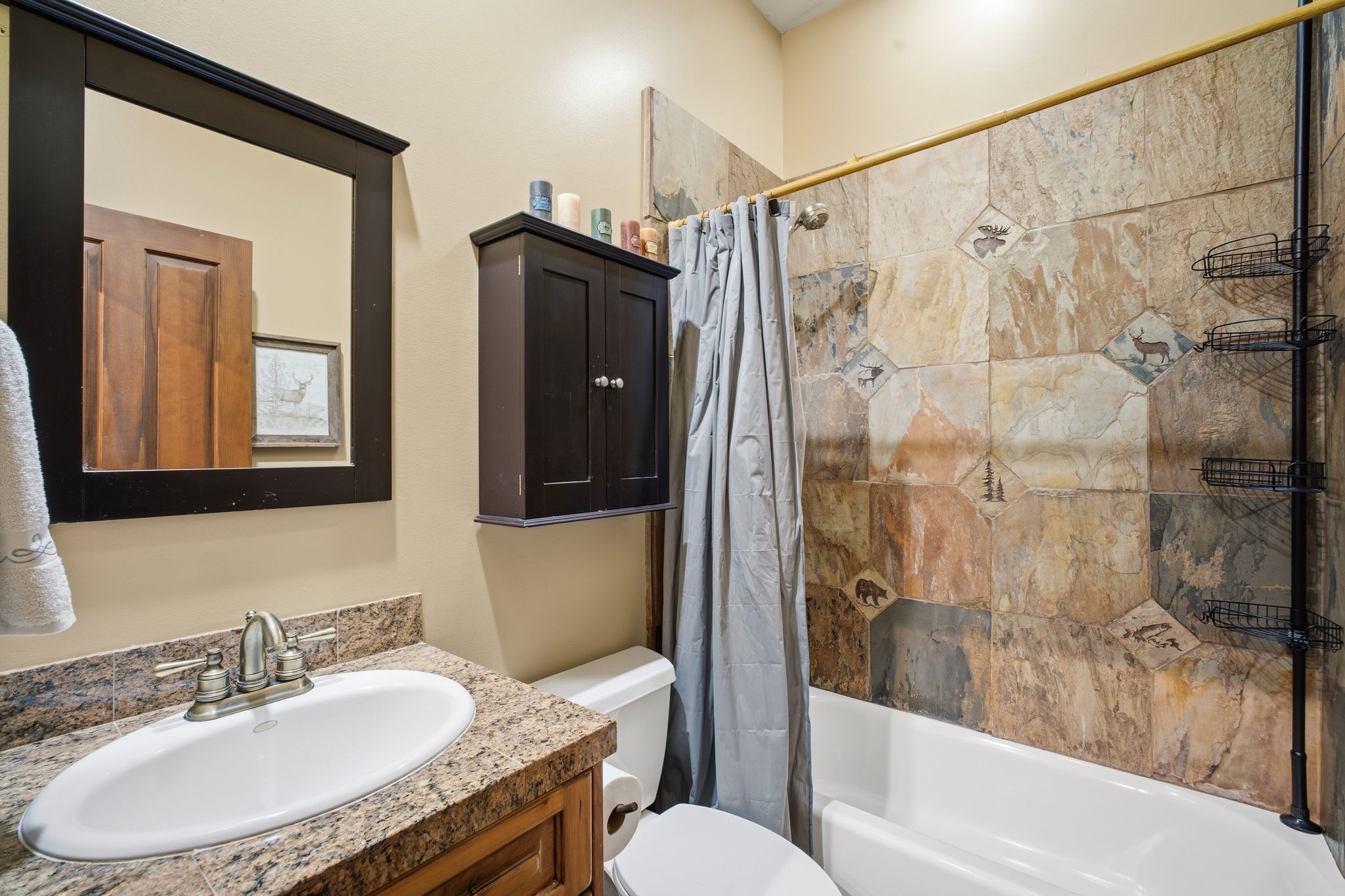 Bathroom featuring a white bathtub with a tile surround, a vanity with an undermount sink, and a framed mirror