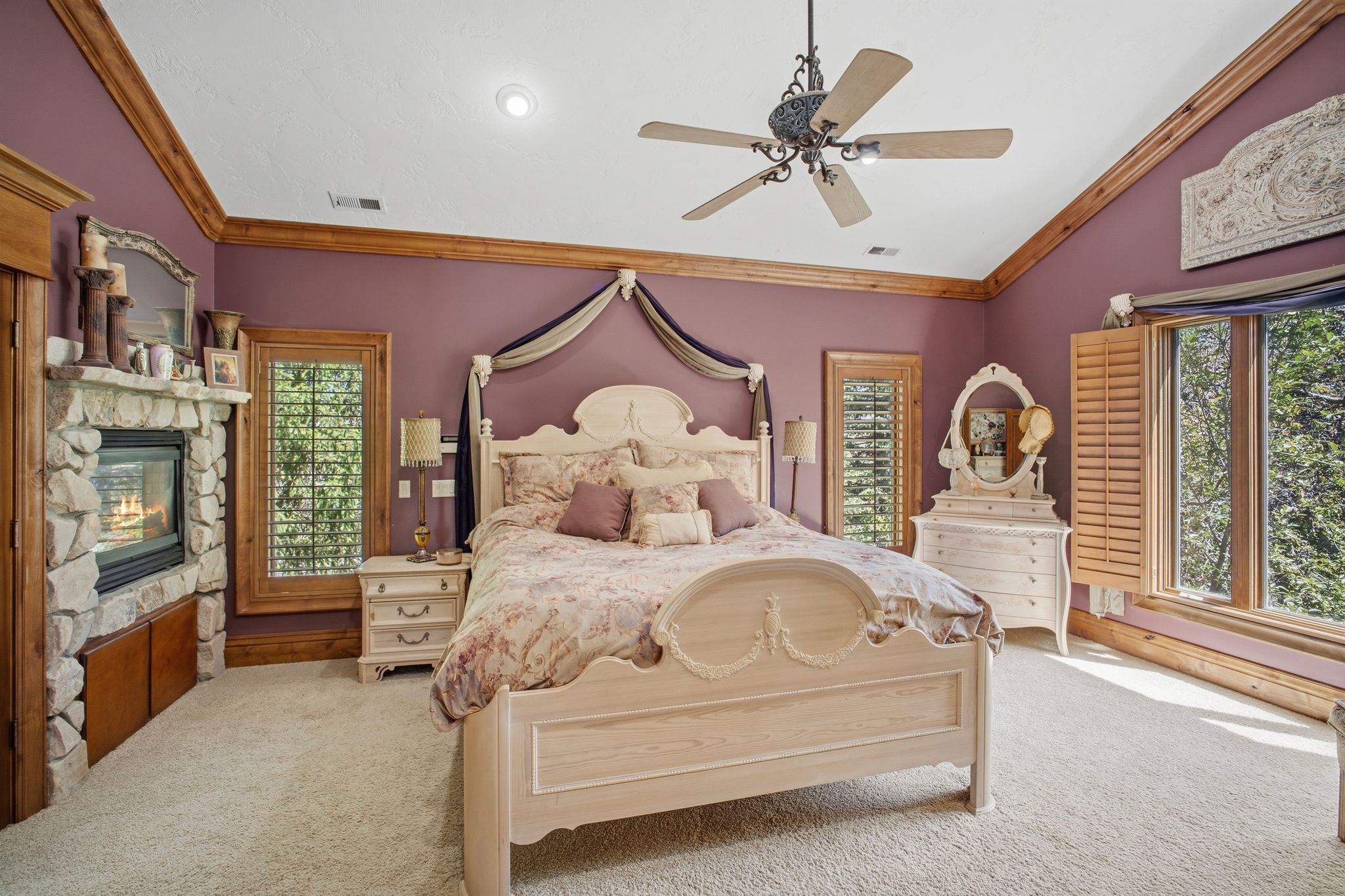 Room featuring a stone-clad fireplace with a built-in hearth, warm wood trim, and multiple windows