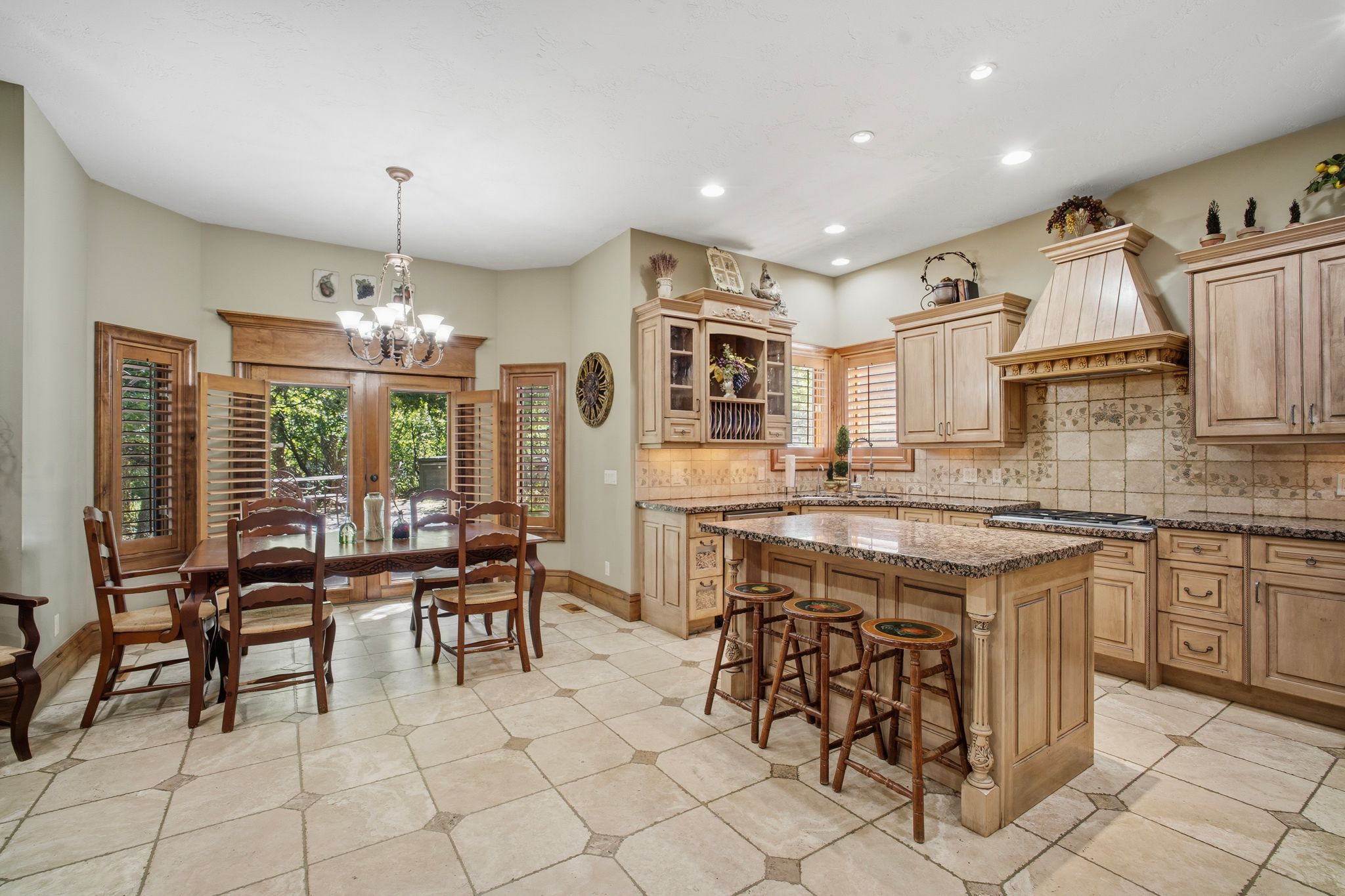Spacious kitchen featuring an island with a breakfast bar, light wood cabinetry, granite countertops, and a tiled backsplash