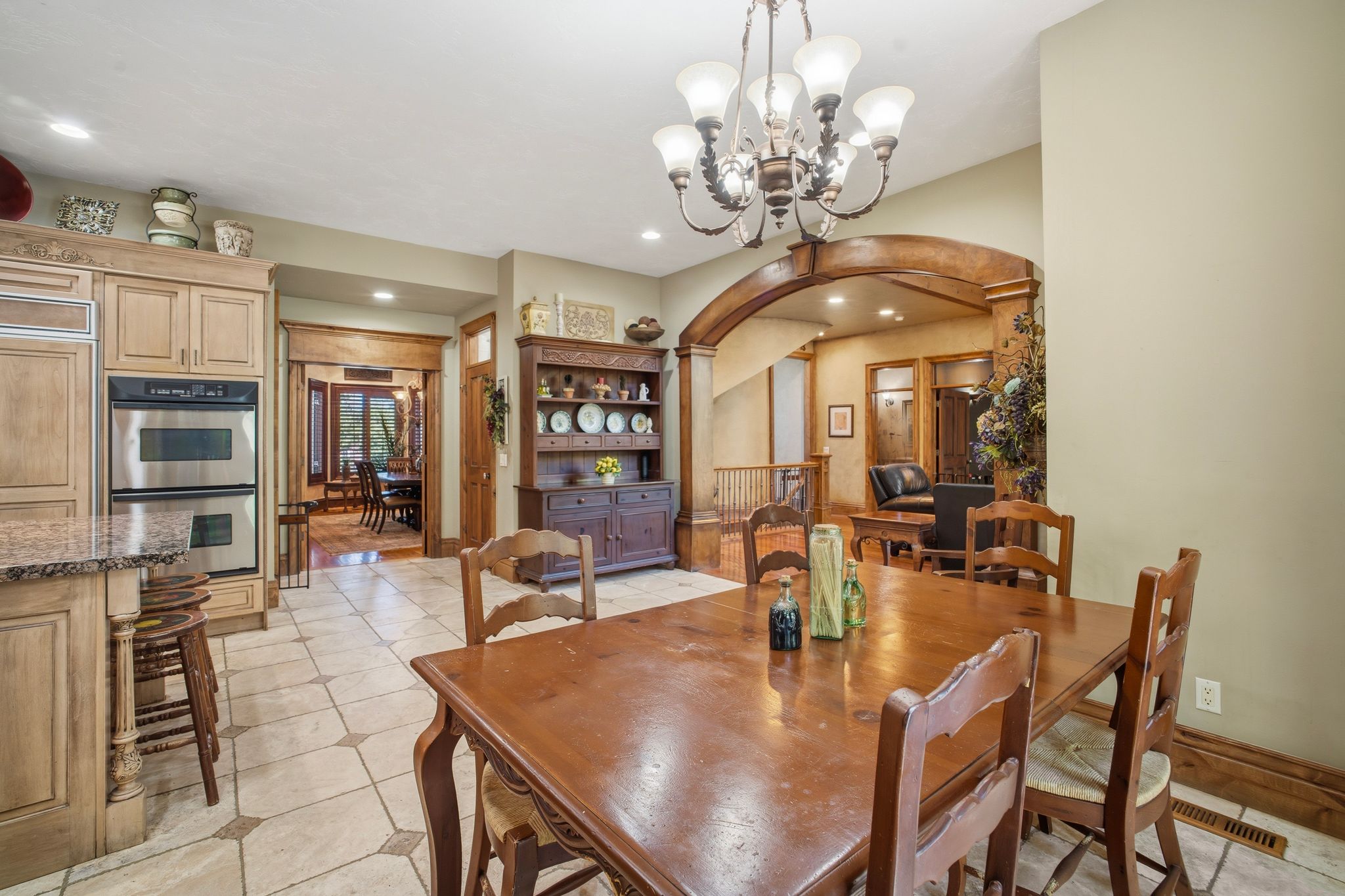 Spacious dining area featuring a chandelier, wood-finish flooring, and an arched entryway